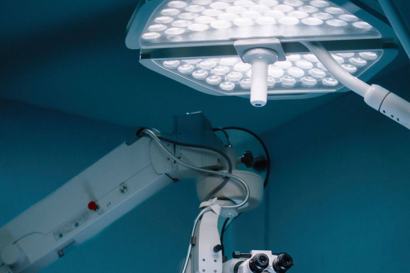Bras articulé d'un appareil de bloc opératoire sous une grande lampe chirurgicale, éclairage bleuté